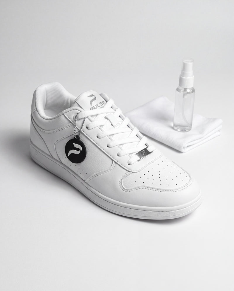 White Pulse Dance Shoes low-top dance sneaker with microfiber cloth and clear spray bottle on a pale gray studio surface