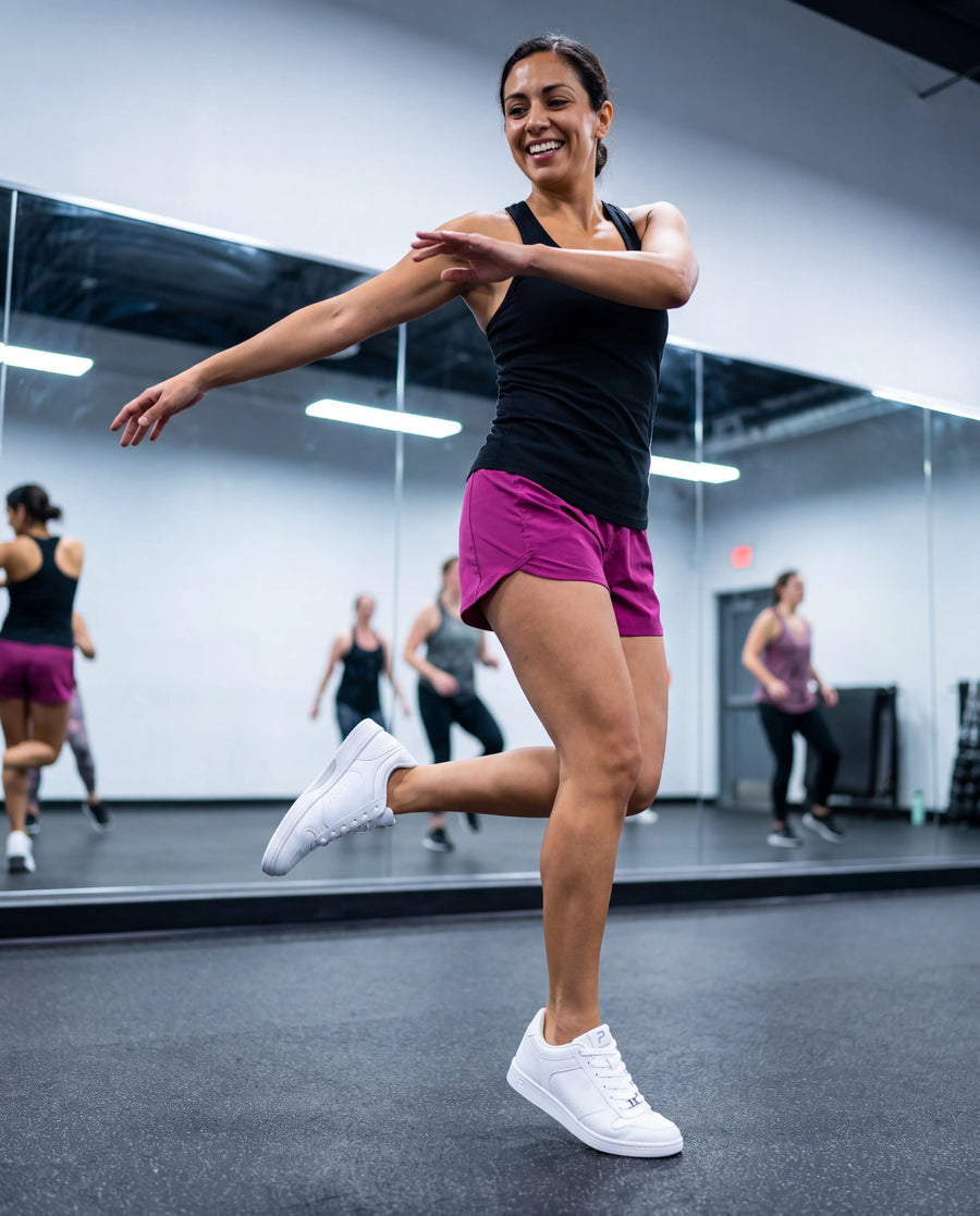 A Zumba instructor dancing in Flow 2 White dance sneakers in a mirrored studio